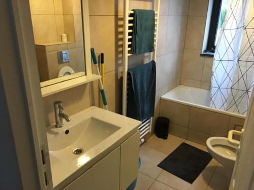 Modern bathroom in Courcelles apartment with sink, toilet, shower, towel rack, and mirror lighting