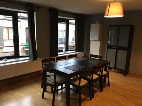 Modern dining area in Courcelles apartment with black table, wooden chairs, and city view windows