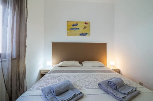 Modern bedroom at Armação Beach Residences with brass headboard, white pillows, patterned bedding, rolled towels, and