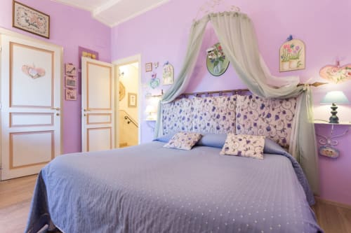 Camera da letto rosa con letto a baldacchino, biancheria blu e arredamento floreale presso il B&B Dormire Assisi ad Assisi, Italia