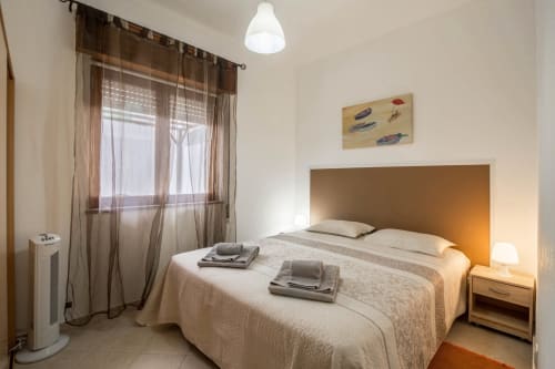 Cozy bedroom at Armação Beach Residences with queen bed, orange headboard, sheer curtains, and modern amenities in Armação de