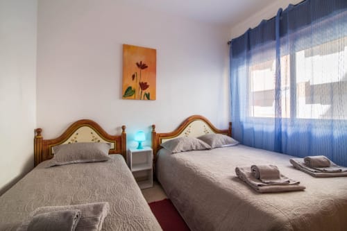 Twin bedroom at Armação Beach Residences with wooden beds, blue curtains, and city view in Armação de Pêra