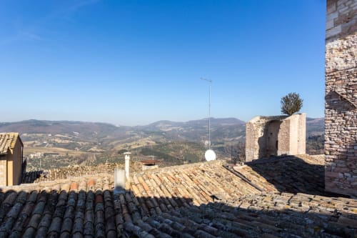 Terrazza panoramica di Assisi con colline ondulate, edifici in pietra e paesaggio montano dal Dormire Assisi