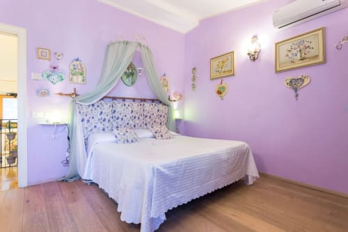 Camera da letto viola con letto a baldacchino e arte botanica incorniciata presso il Dormire Assisi B&B ad Assisi, Italia