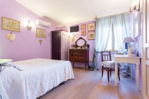Affascinante camera in tonalità lavanda presso Dormire Assisi B&B con letto bianco, mobili in legno e vista sulle montagne