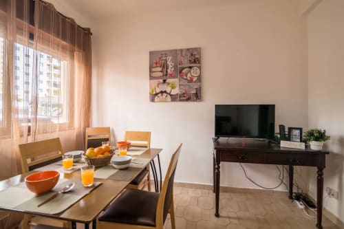 Modern apartment dining and living area at Armação Beach Residences with dining table, TV, city view windows