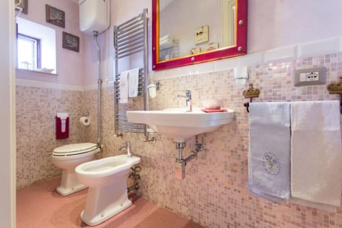 Bagno con piastrelle rosa, lavabo, WC, bidet e doccia presso il B&B Dormire Assisi ad Assisi