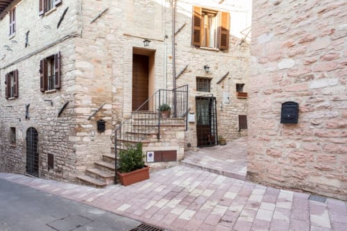 Ingresso storico in pietra della corte del Dormire Assisi B&B ad Assisi, Italia con architettura tradizionale e persiane in legno