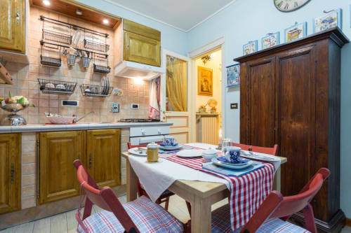 Accogliente zona cucina-sala da pranzo in B&B ad Assisi con mobili in legno, pareti blu, tavolo apparecchiato con runner rosso a righe e stile tradizionale
