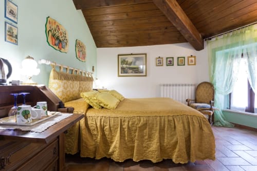 Camera da letto accogliente del B&B di Assisi con biancheria gialla, travi in legno e arredamento tradizionale italiano con vista sulla città