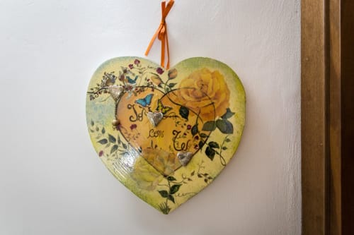 Decorazione in legno a forma di cuore con rose gialle e motivi botanici appesa nella camera del B&B di Assisi