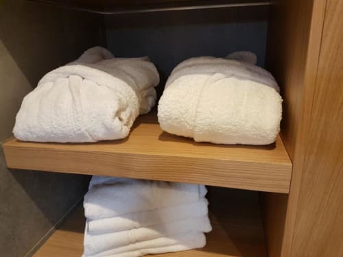 Serviettes blanches roulées empilées sur une étagère en bois dans la salle de bains de l'appartement Résidence Lésia, Corbara