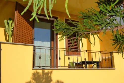 Balcon jaune vif avec rampe métallique et plantes suspendues à l'Affittacamere Al Mare, Torre Grande Oristano
