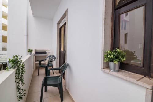 Narrow balcony seating area at Armação Beach Residences with black chairs, potted plants, and city view in Armação de Pêra