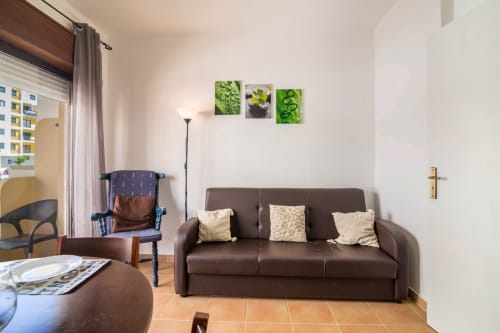 Modern apartment living room at Armação Beach Residences with brown sofa, sitting area, and city view in Armação de Pêra
