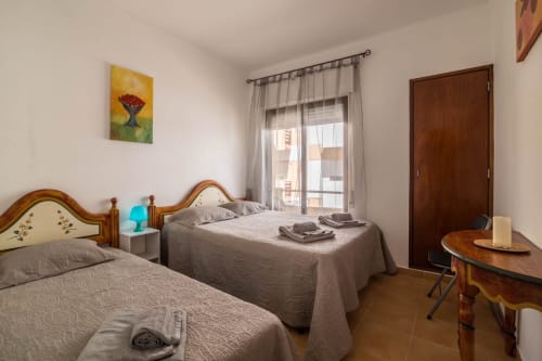 Twin bedroom at Armação Beach Residences with wooden headboards, gray bedding, balcony view, and wooden furniture in Armação