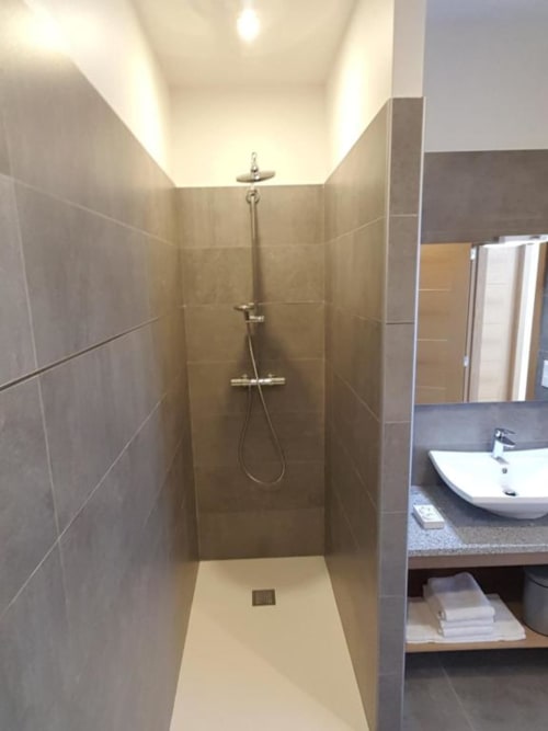 Douche moderne avec pommeau cascade dans l'appartement Corbara à la Résidence Lésia, carrelage mural et coin lavabo