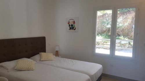 Chambre lumineuse à la Résidence Lésia à Corbara avec lits jumeaux, tête de lit marron, oreillers jaunes et vue sur mer