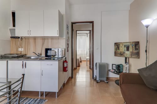 Modern T1 apartment kitchen and living area at Armação Beach Residences with white cabinetry, dining space, and city views