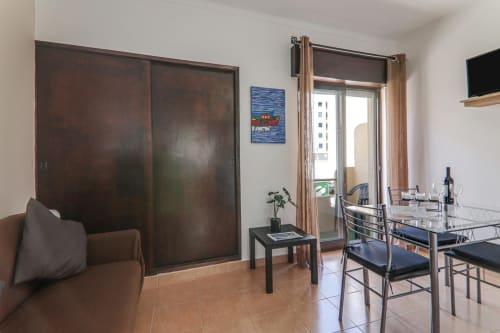 Modern suite with dark wood wardrobe, dining area, and balcony overlooking Armação de Pêra at Armação Beach Residences