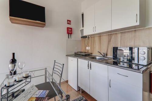 Modern kitchenette in Suite T1 at Armação Beach Residences with white cabinetry, dining area, and city view, Armação de Pêra