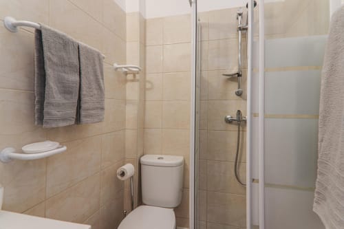Modern bathroom with shower at Armação Beach Residences, featuring tiled walls, toilet, towel rack, and shower enclosure in