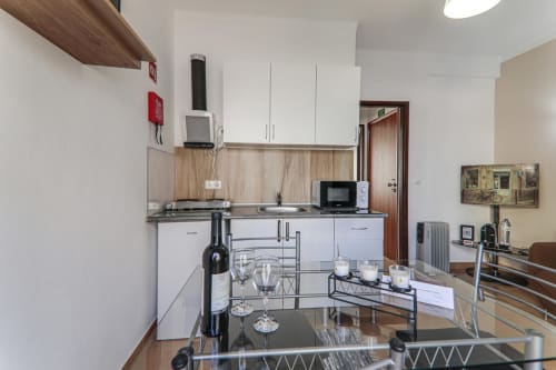 Modern kitchen and dining area in Armação Beach Residences Suite T1 with white cabinets, stainless steel appliances, and