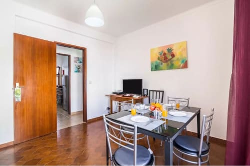 Dining area in Armação Beach Residences T2 apartment with table, chairs, TV, and city view decor