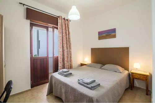 Bedroom at Armação Beach Residences with queen bed, wooden nightstand, pendant light, and balcony access in Armação de Pêra