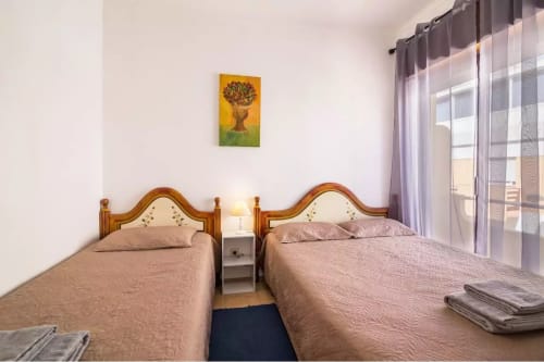 Twin beds in apartment at Armação Beach Residences, Portugal, with wooden headboards and balcony access