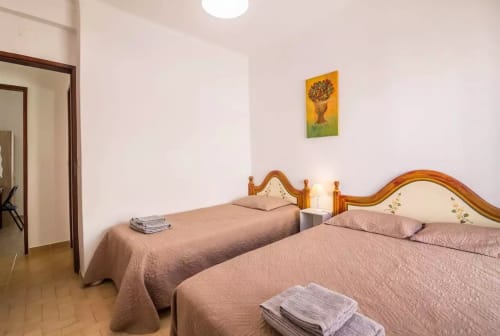 Twin bedroom at Armação Beach Residences with wooden beds, bedside lamps, and city view artwork in Armação de Pêra