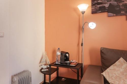 Cozy apartment corner at Armação Beach Residences with orange walls, floor lamp, desk, brown sofa, and city view in Armação