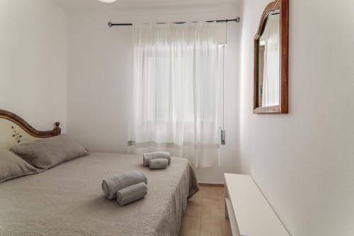 Bright bedroom at Armação Beach Residences with double bed, wooden frame, white sheer curtains, mirror, and modern