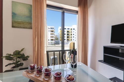 Modern apartment suite at Armação Beach Residences with city view, dining area, wine glasses, and balcony overlooking