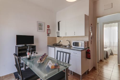 Modern studio apartment kitchenette and dining area at Armação Beach Residences with flat-screen TV, microwave, and city