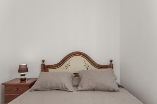 Cozy bedroom at Armação Beach Residences with wooden headboard, gray bedding, and nightstand lamp in Armação de Pêra