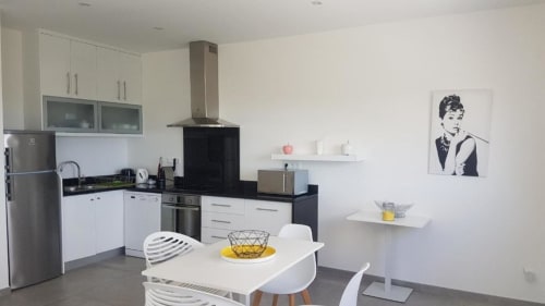 Cuisine moderne à la Résidence Lésia à Corbara avec mobilier blanc, plan de travail noir, table à manger et décoration contemporaine