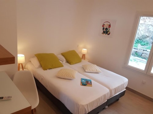 Chambre moderne à la Résidence Lésia à Corbara avec lits jumeaux, oreillers olive et vue sur le jardin