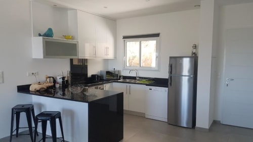 Cuisine moderne de la Résidence Lésia BnB à Corbara avec comptoirs en granit noir, appareils en acier inoxydable et armoires blanches