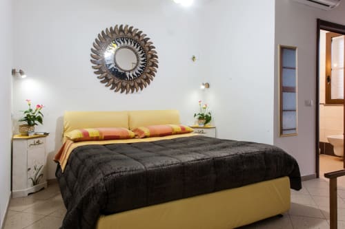 Camera doppia gialla ad Al Mare & Acquamarina con coperta nera, specchio decorativo, due comodini con fiori e