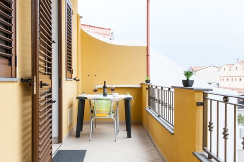 Balcon jaune ensoleillé avec table à manger à l'Affittacamere Al Mare à Torre Grande, Oristano. Chambre avec vue sur le jardin et mobilier