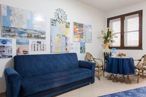 Coin lounge accueillant à l'Affittacamere Al Mare à Torre Grande avec canapé bleu, table ronde, cartes de voyage et fleurs