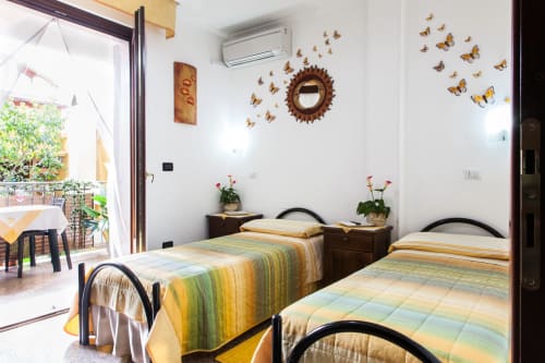 Chambre twin aux courtepointes colorées, décor papillon et vue sur balcon à l'Affittacamere Al Mare de Torre Grande