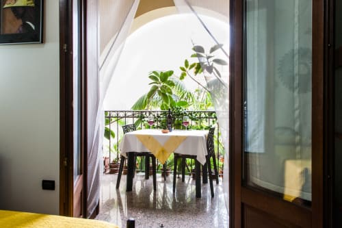 Vue du balcon de la chambre familiale à Affittacamere Al Mare avec table, chaises et plantes de jardin luxuriantes à Torre Grande, Oristano