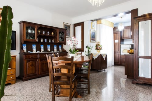 Salle à manger élégante avec mobilier en bois, vitrine et fleurs fraîches à Affittacamere Al Mare, Torre Grande