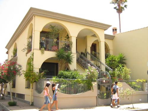 Hôtel familial de couleur crème avec balcons cintrés et palmiers à Torre Grande, Oristano