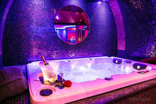 Salle de bain spa privée luxueuse aux néons violets et champagne à L'Insolite, Toulouse