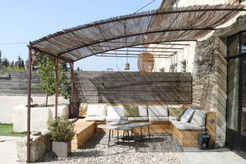 Terrasse extérieure avec sièges en bois, pergola ombragée et éclairage décoratif à l'hôtel Mas Lafleur à Châteaurenard
