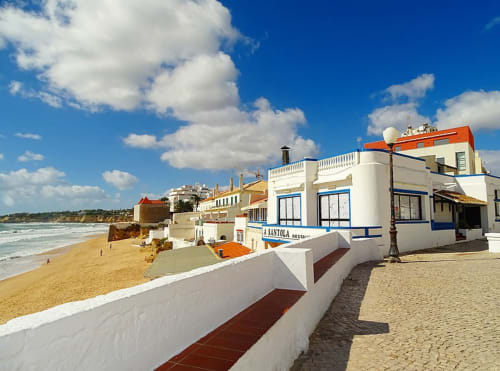 Residências beira-mar de Armação com edifícios brancos, portas azuis e praia arenosa em Armação de Pêra, Portugal