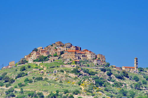 Village perché de Corbara avec ses bâtiments en pierre traditionnels et le clocher de l'église sous un ciel bleu dégagé